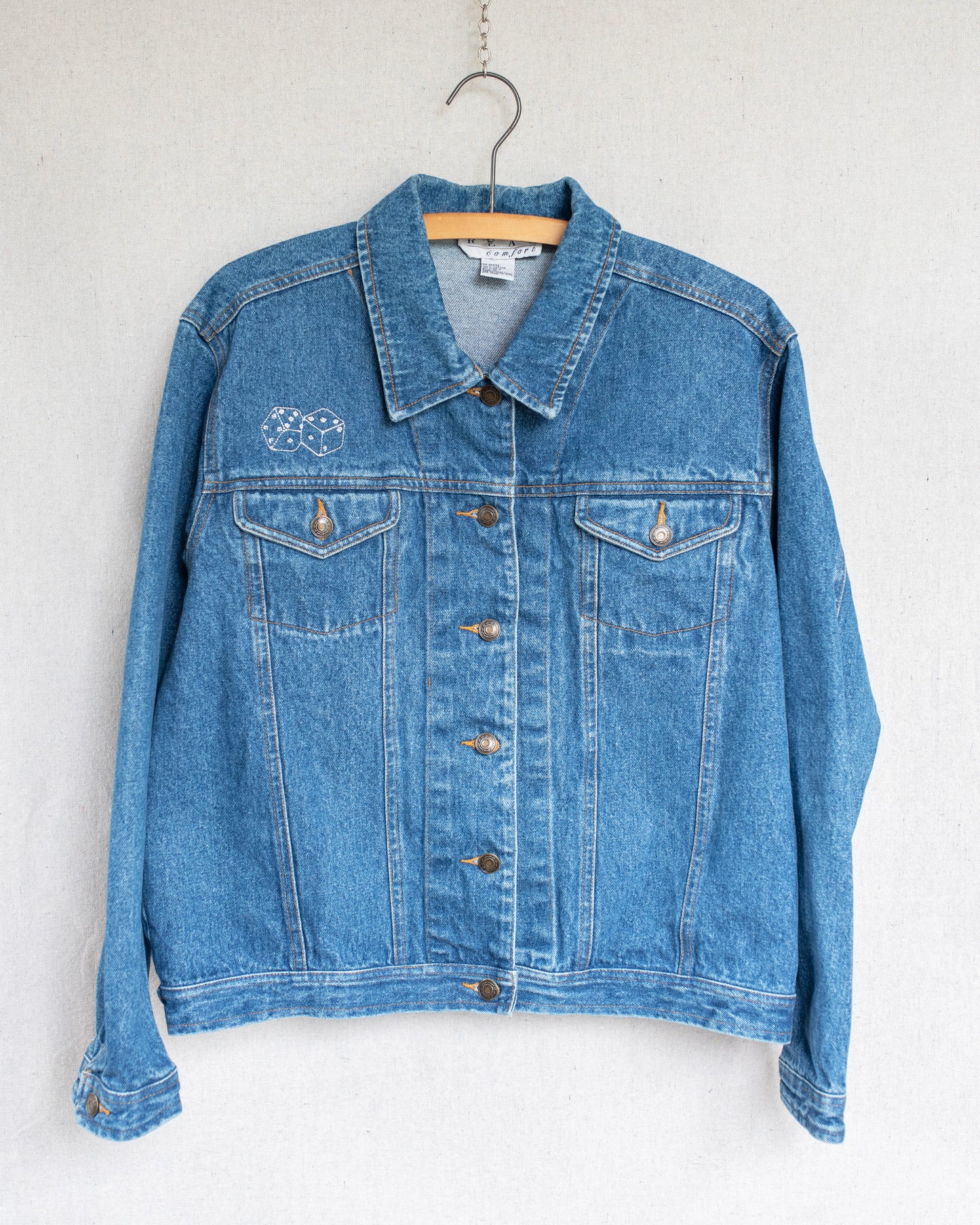 Blue denim jacket on a hanger against a white background