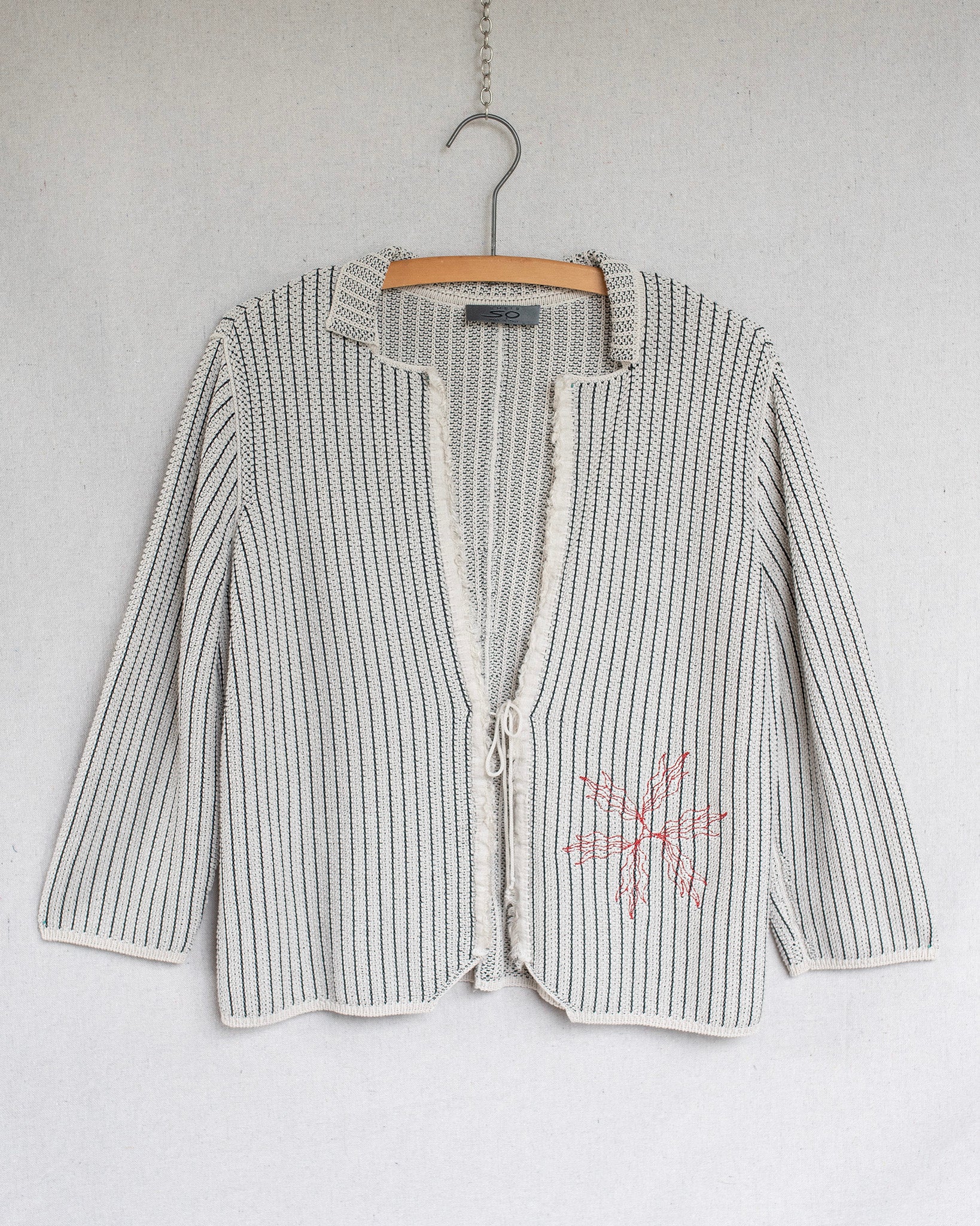 Striped cardigan with a floral design on a hanger against a white background
