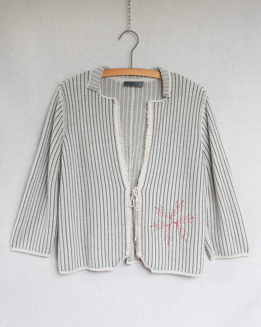 Striped cardigan with a floral design on a hanger against a white background