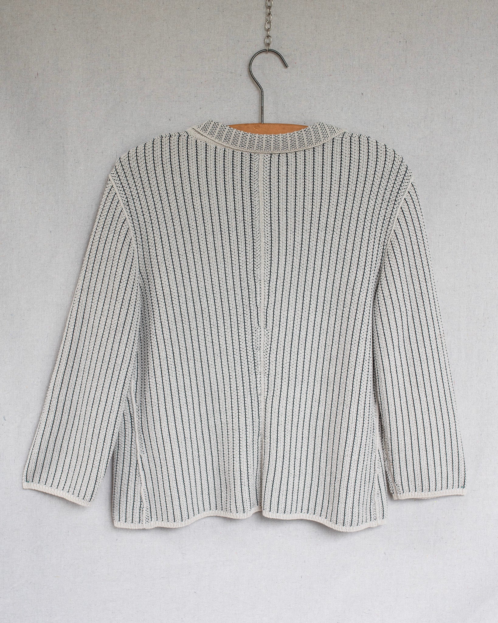 Textured sweater on a hanger against a plain background