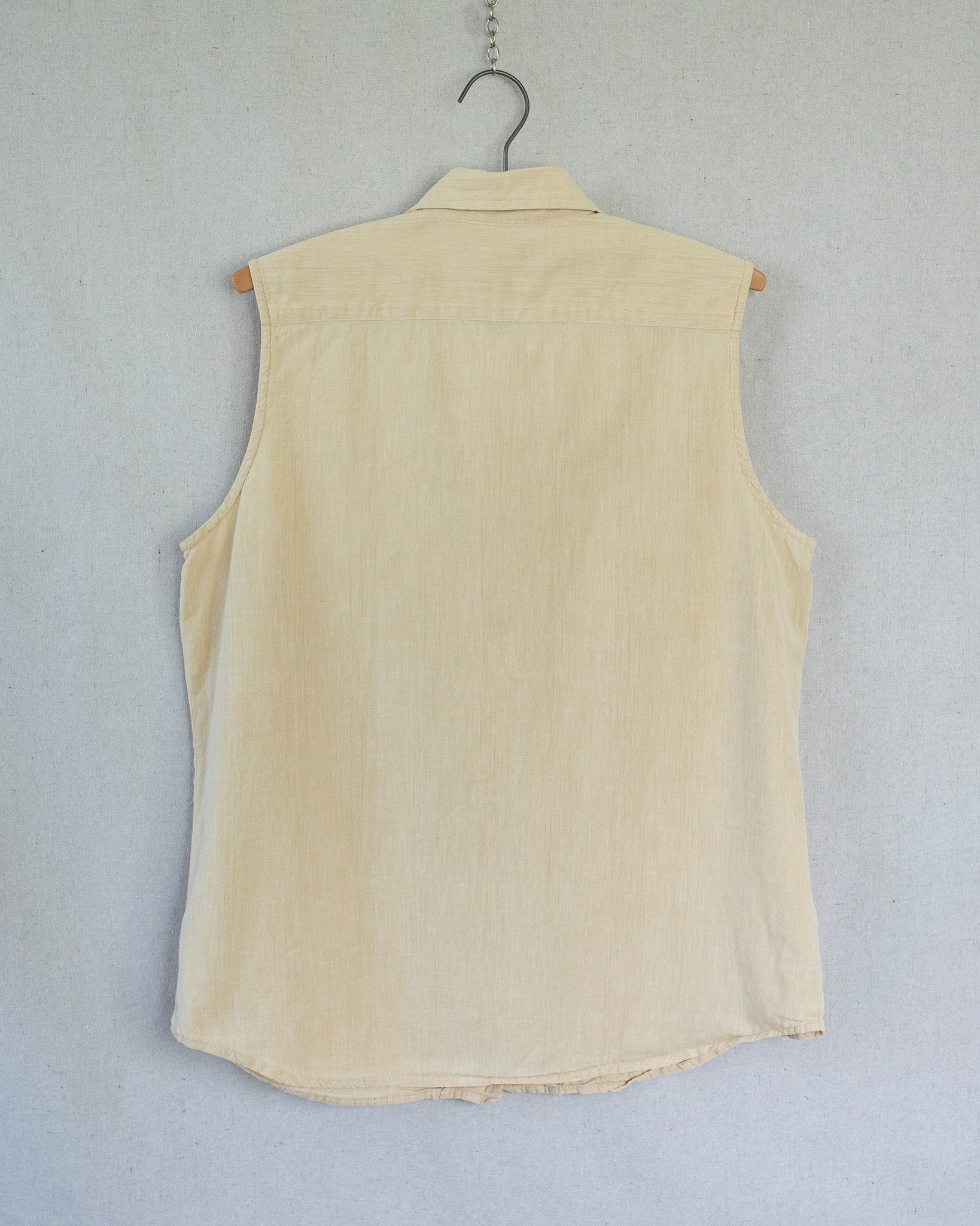 Yellow sleeveless shirt on a hanger against a light gray background