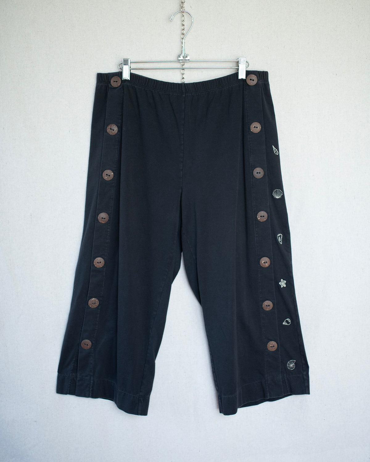 Black stretchy hanging capris with small seashell embroideries.