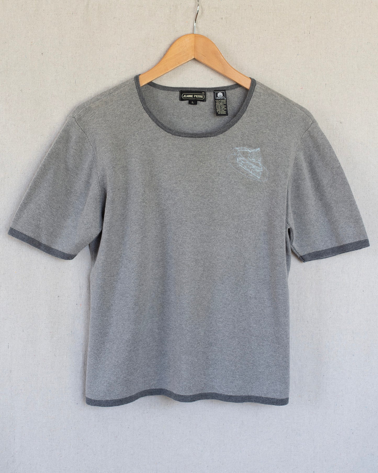 Gray t-shirt with embroidery on a hanger against a white background