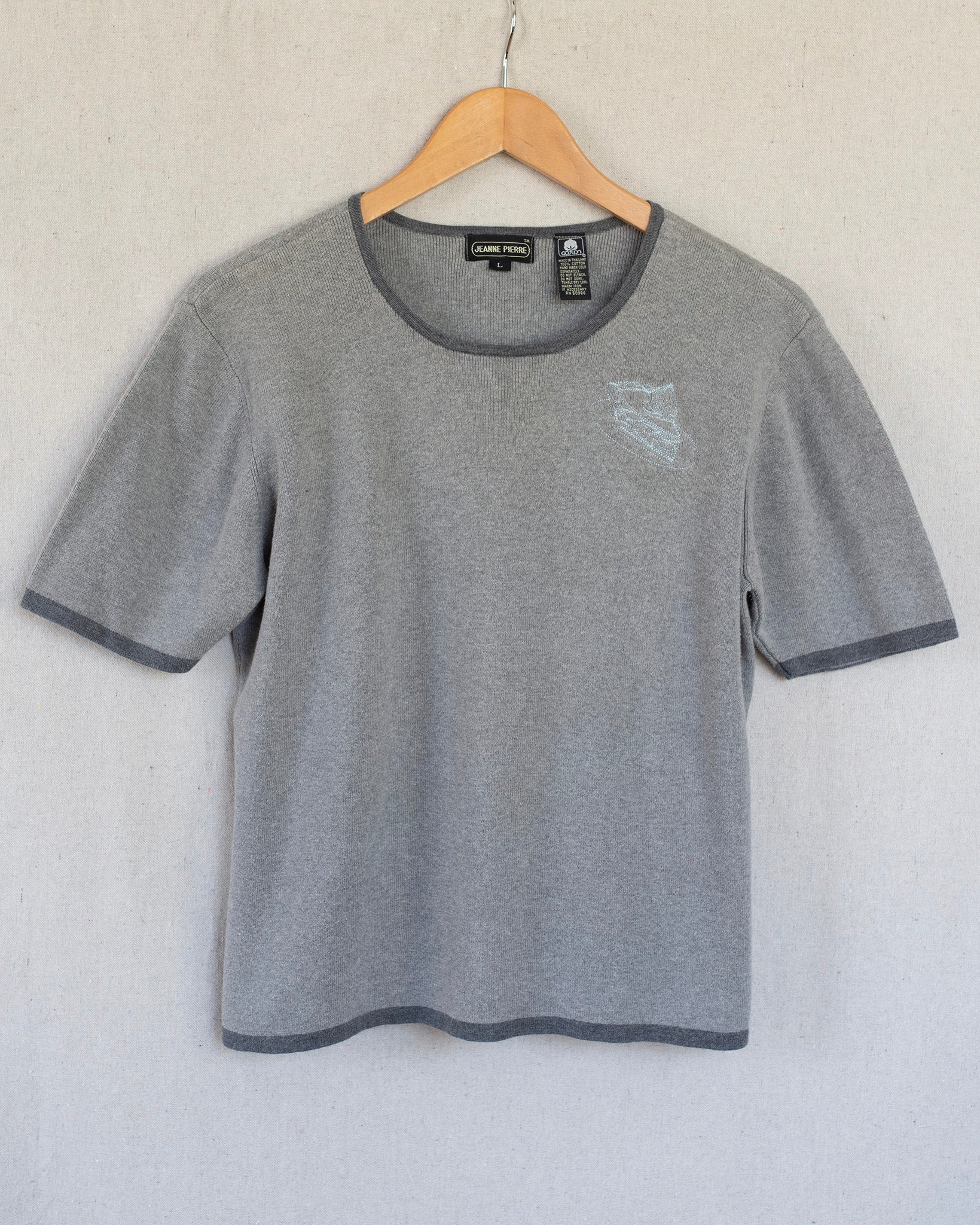 Gray t-shirt with embroidery on a hanger against a white background