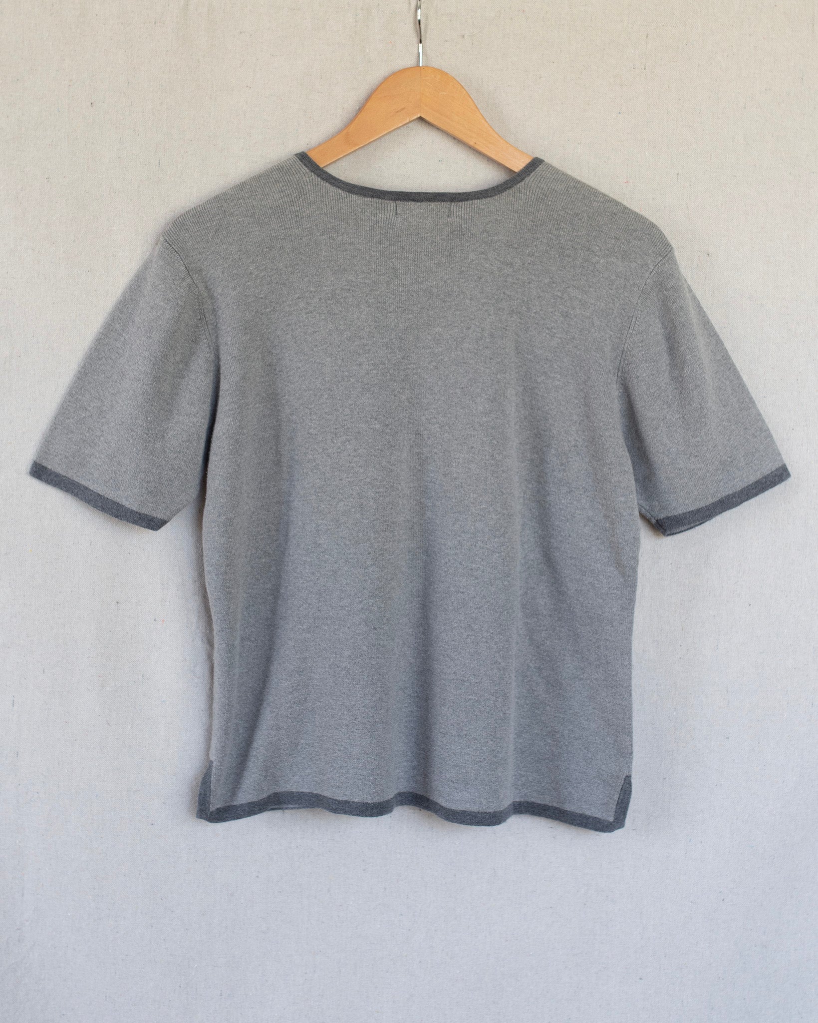Gray t-shirt on a wooden hanger against a light gray background