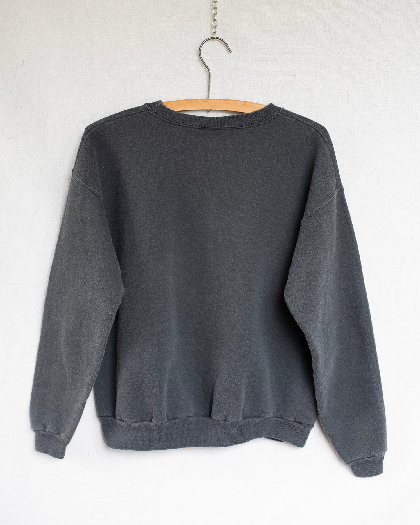 Black sweatshirt on a hanger against a white background