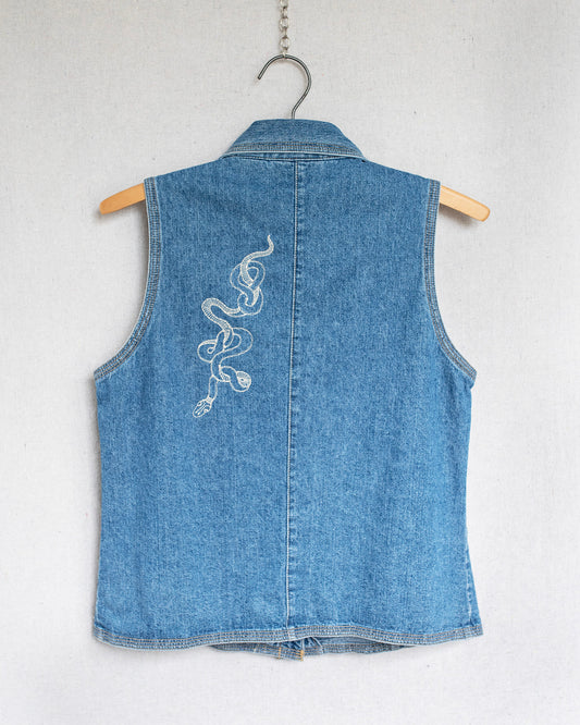Blue denim vest with a snake embroidery on a hanger against a white background