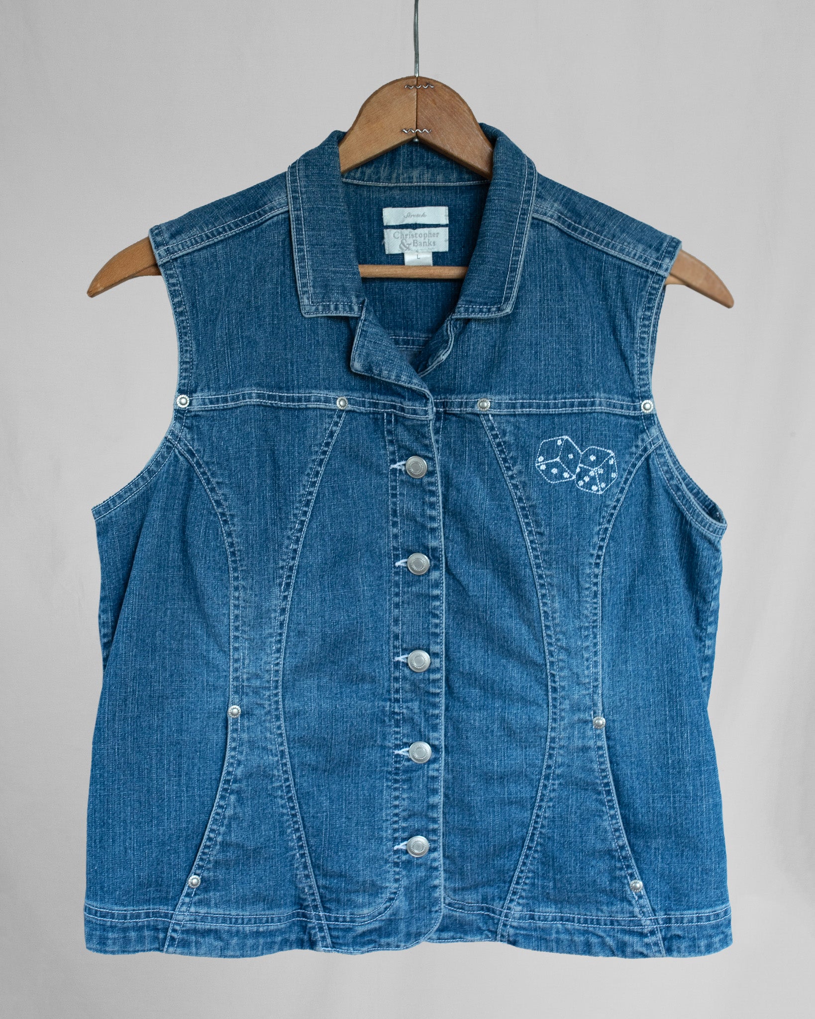 Blue denim vest with embroidery on a hanger against a gray background