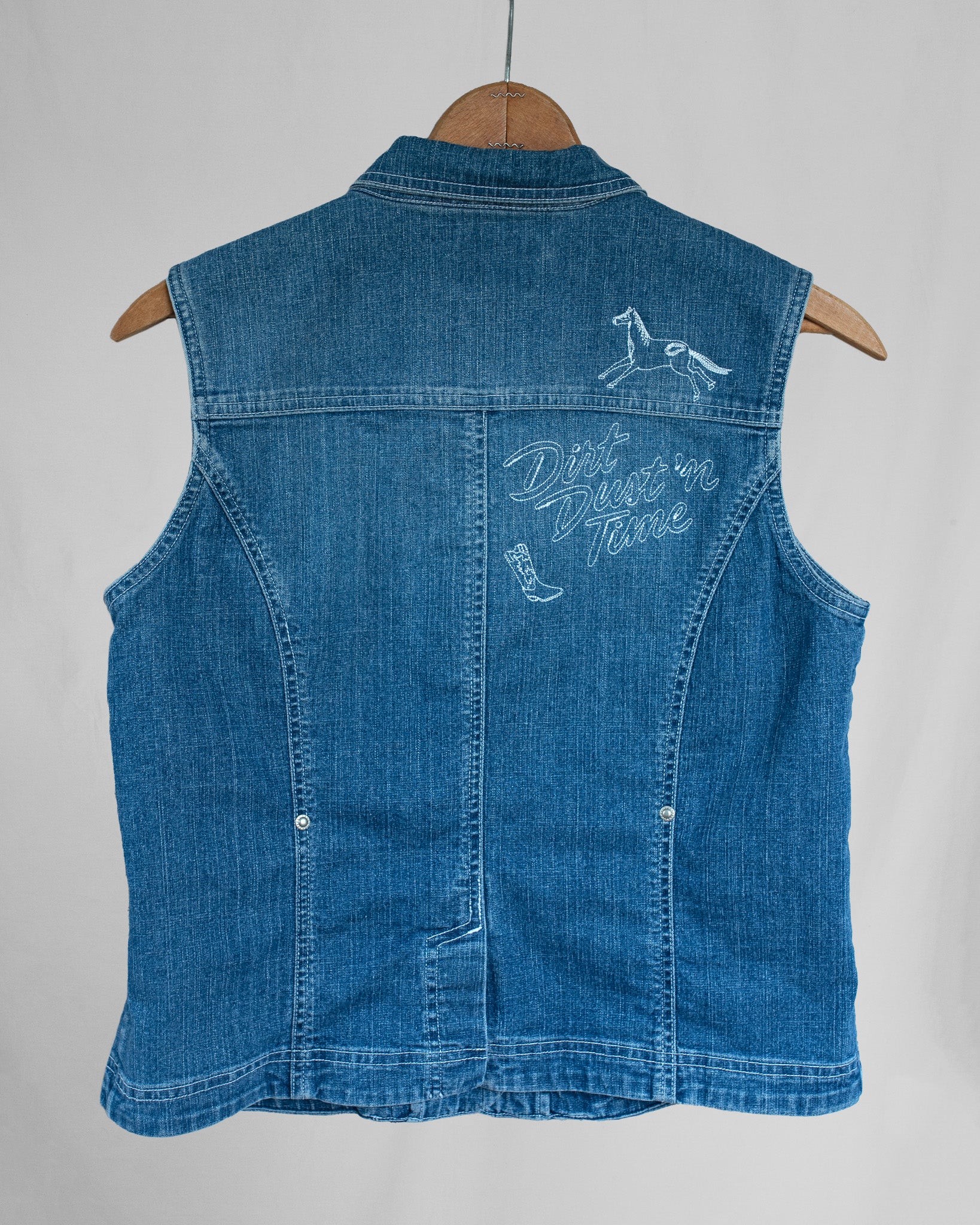 Blue denim vest with embroideries on a white background