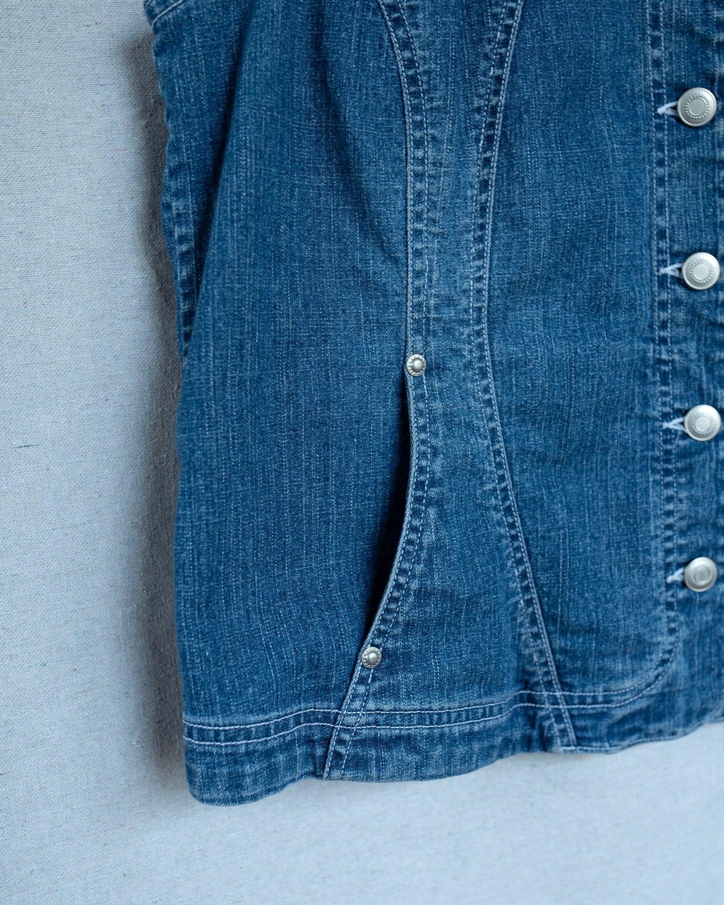 Close-up of a blue denim jacket with button details on a gray background