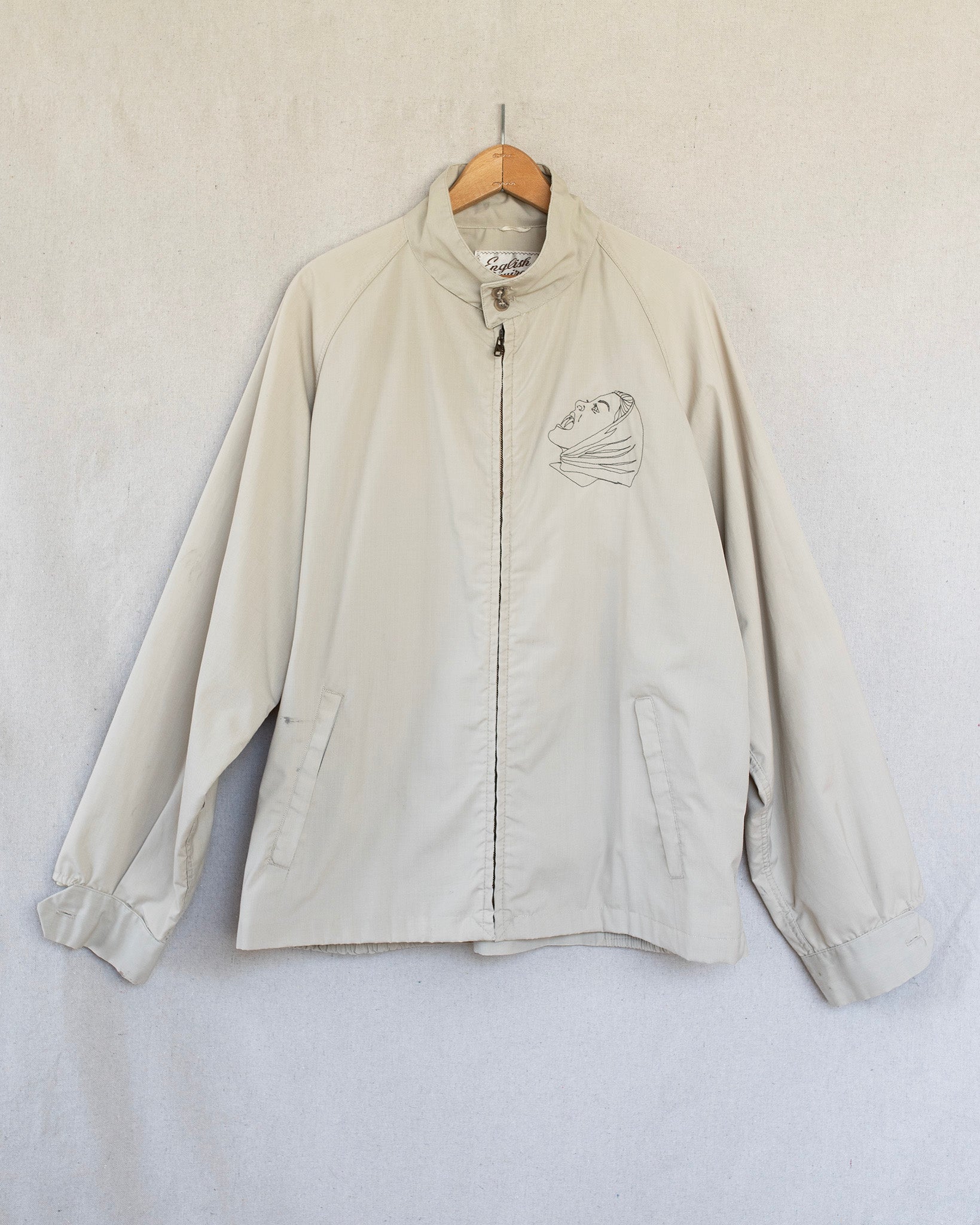 Beige jacket with a small embroidery on a white background
