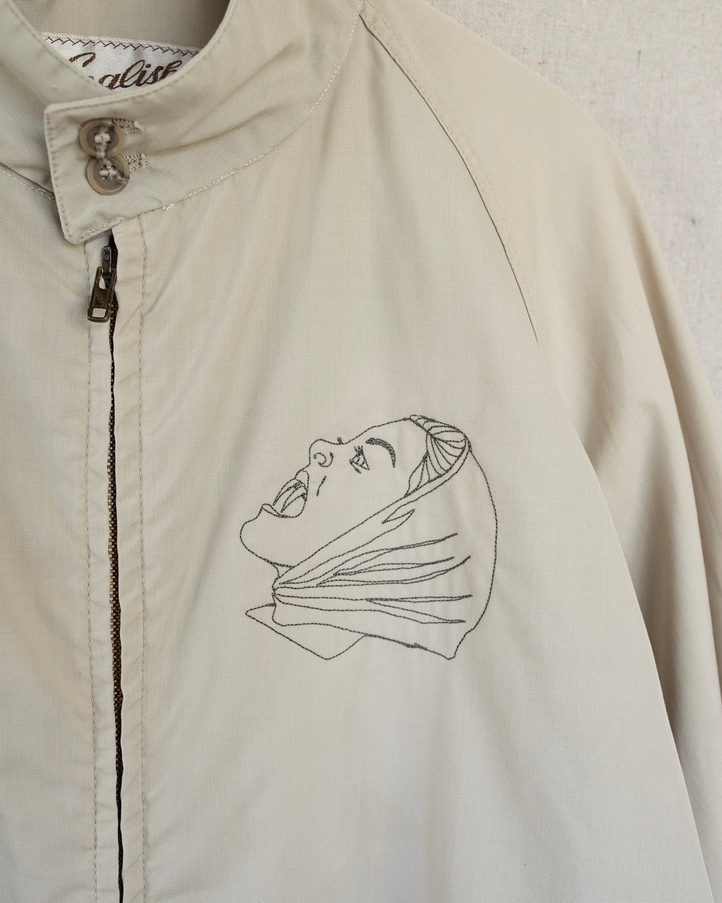 Beige jacket with an embroidered design on a white background