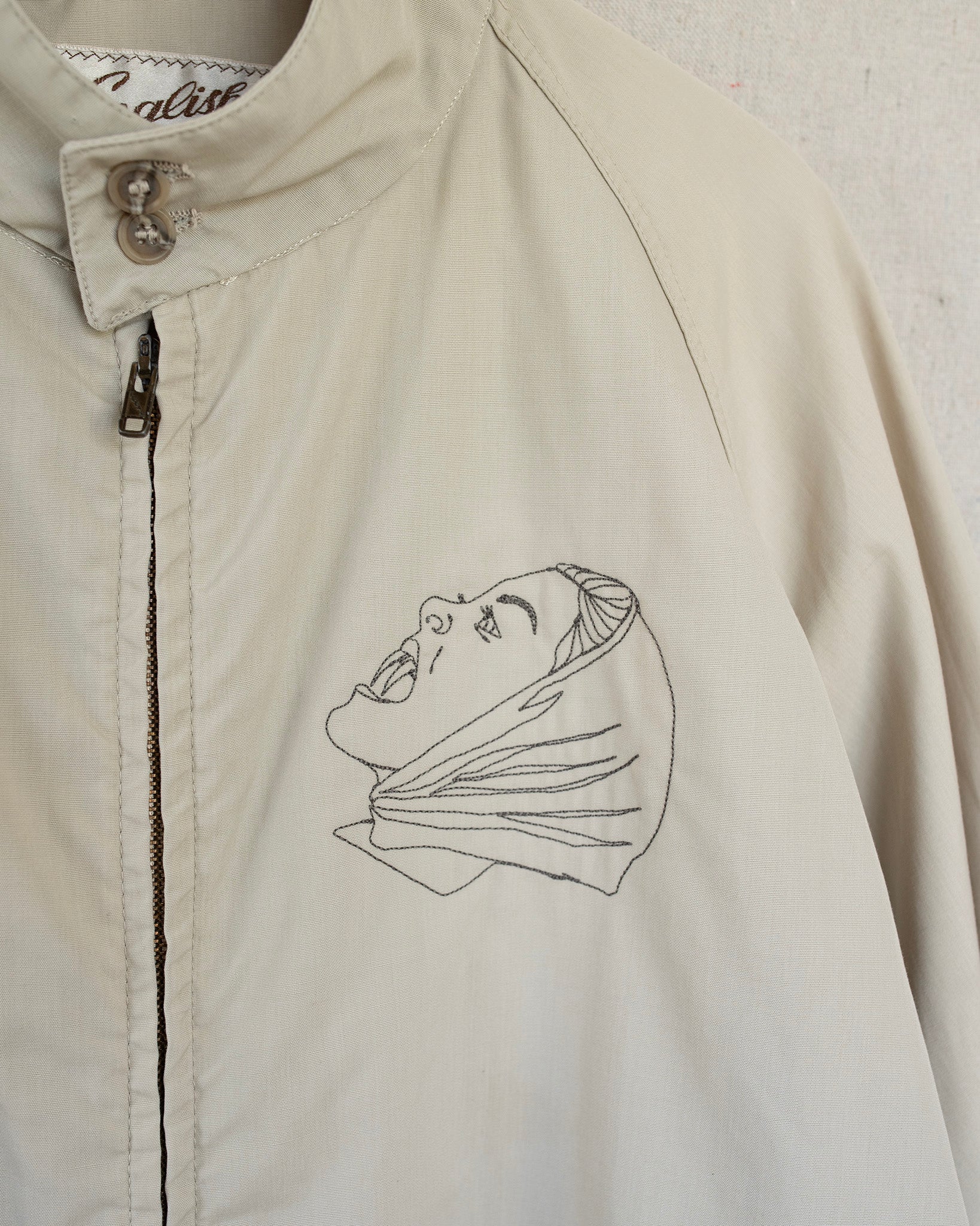 Beige jacket with an embroidered design on a white background