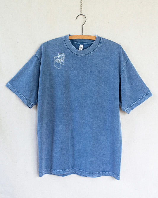 Blue t-shirt with a lawn chair embroidery on a hanger against a white background