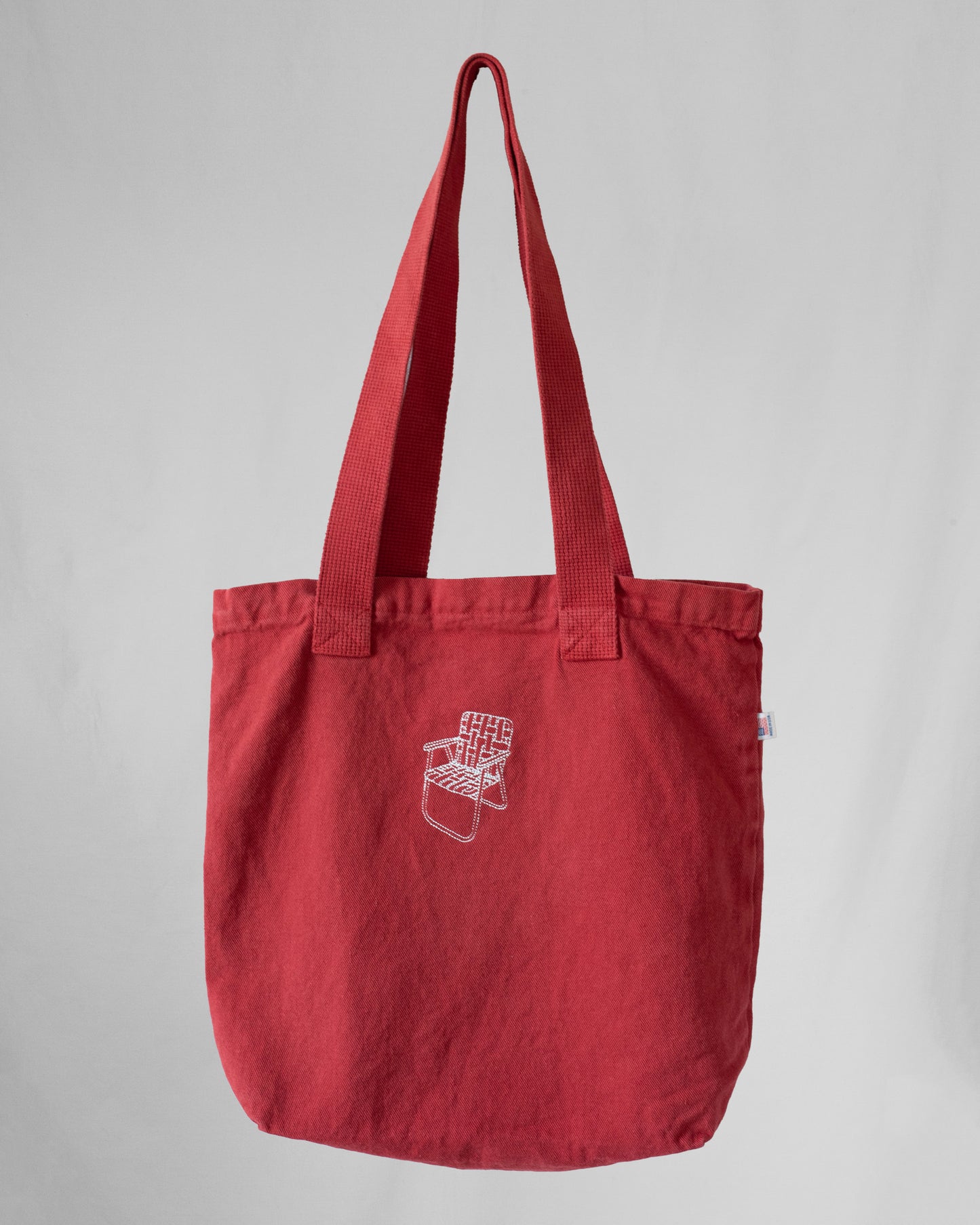 Red tote bag with a lawn chair embroidery on a gray background