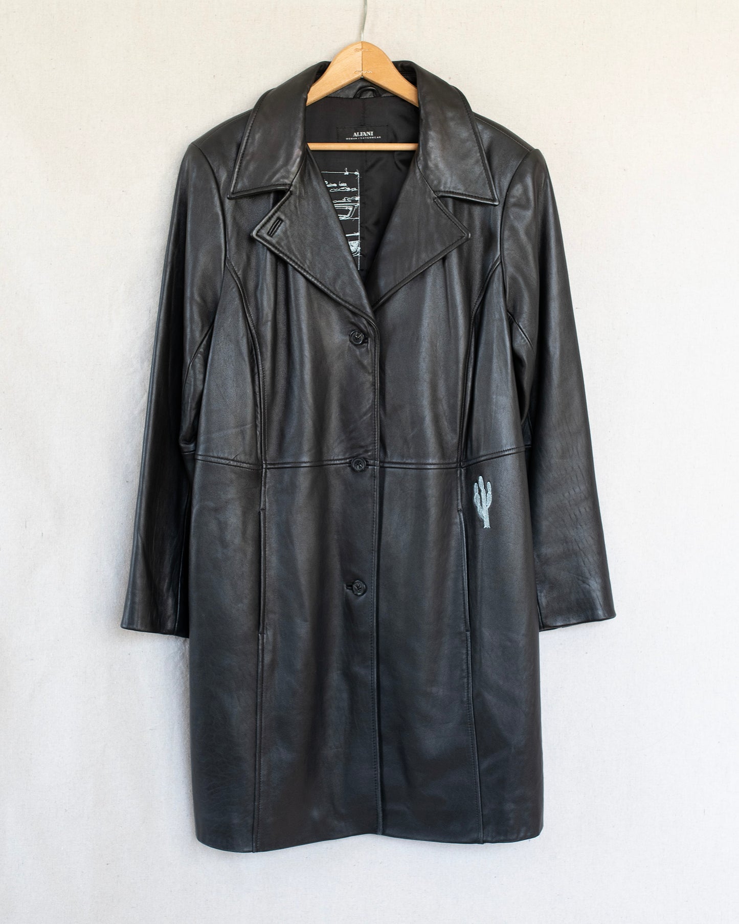 Black leather coat on a hanger against a white background