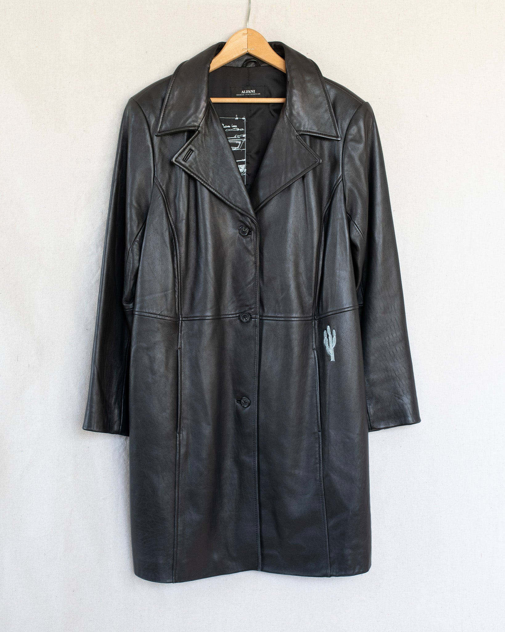 Black leather coat on a hanger against a white background
