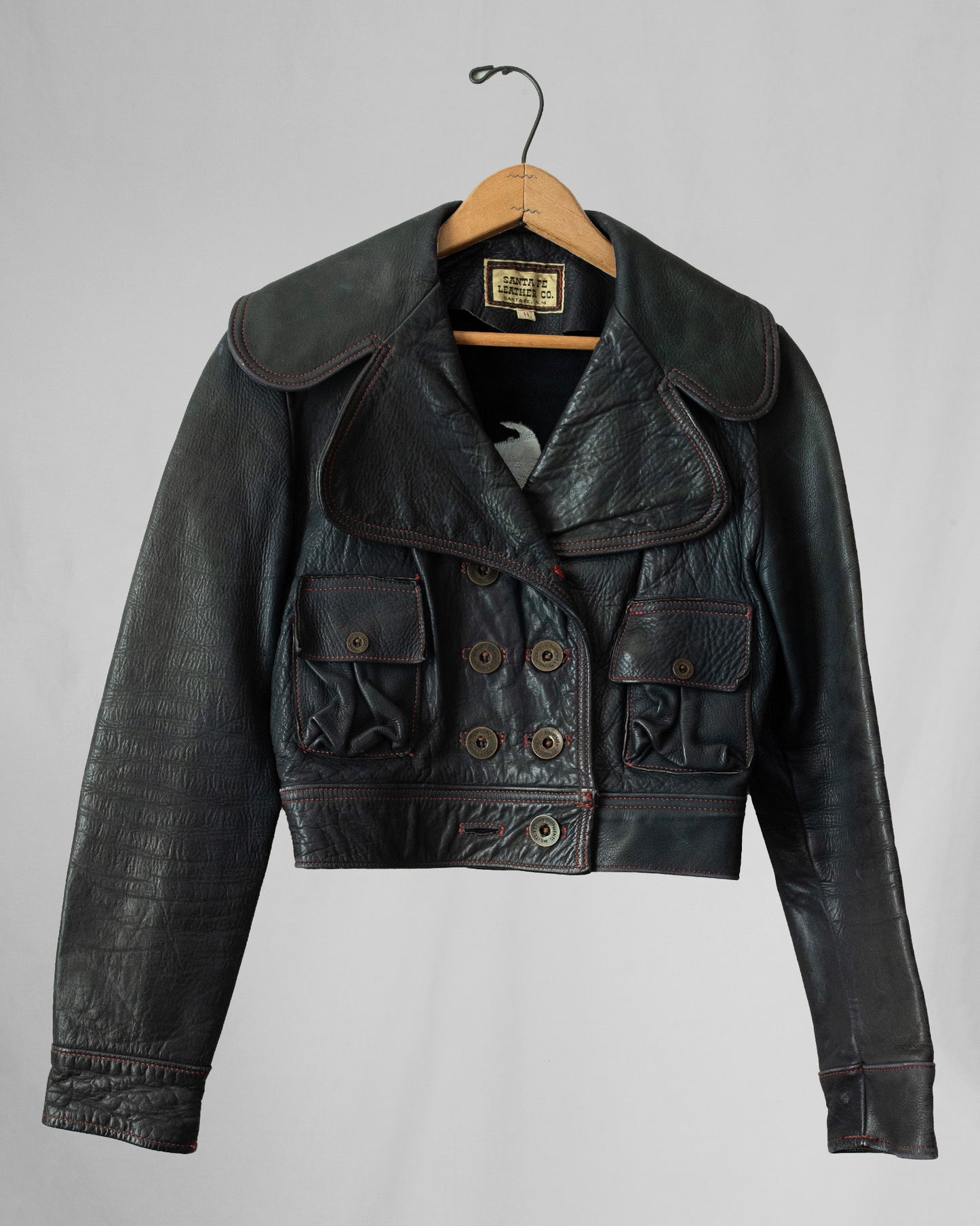 Black leather jacket on a hanger against a gray background