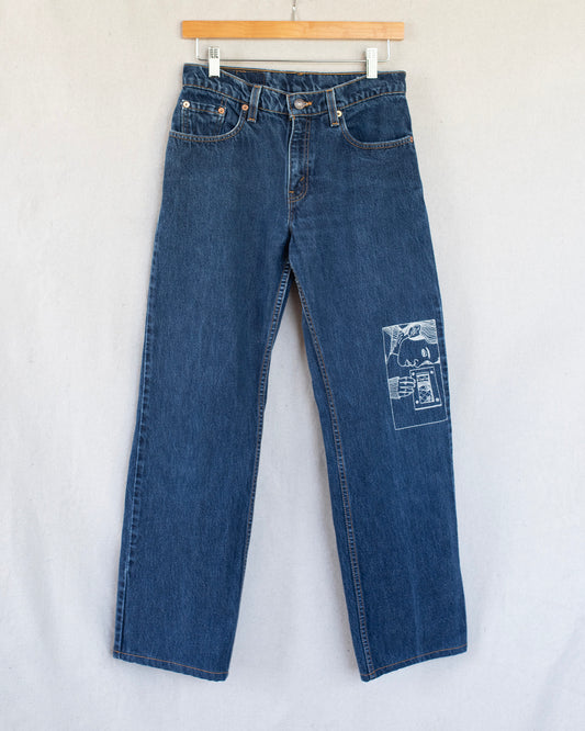 Blue jeans with an embroidery on one leg on a white background
