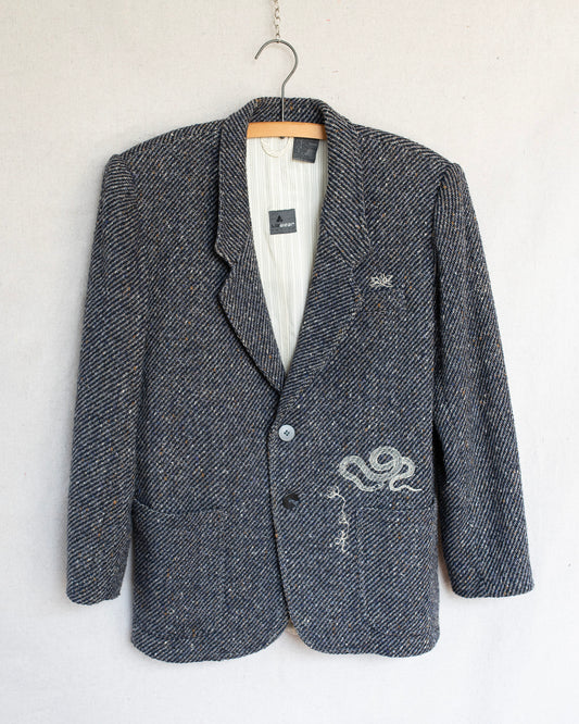 Gray blazer with embroideries on a hanger against a white background