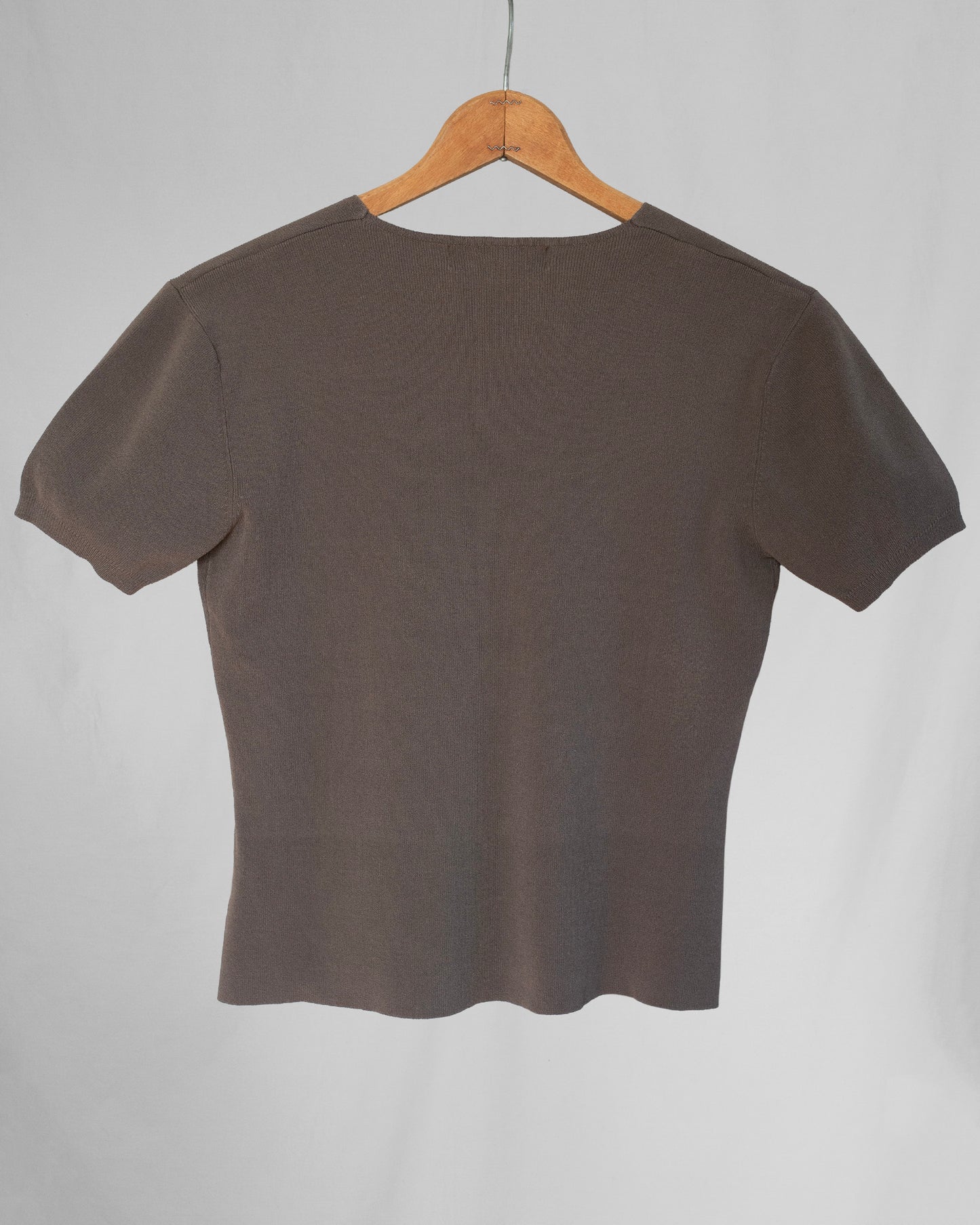 Brown top on a wooden hanger against a gray background