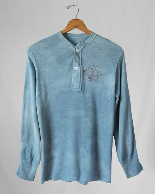 Blue long-sleeve shirt with an embroidery on a hanger against a gray background