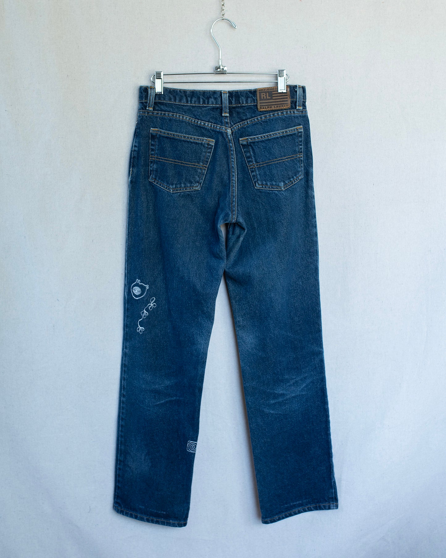 Blue jeans on a hanger against a white background