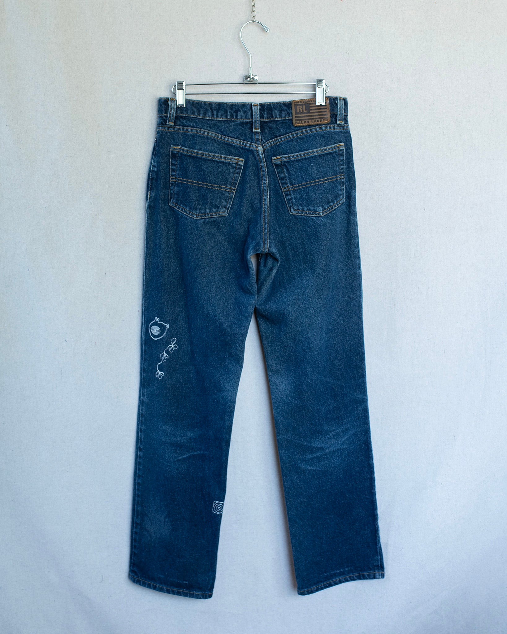 Blue jeans on a hanger against a white background