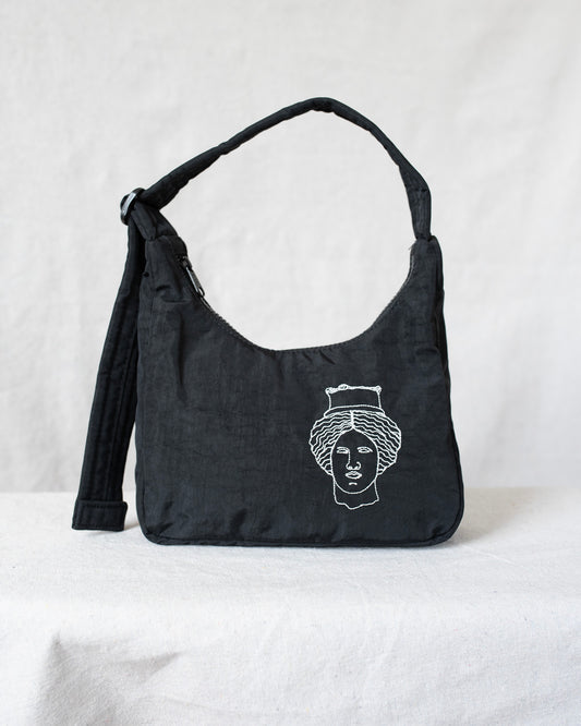 Black shoulder bag with white face design on a light gray background