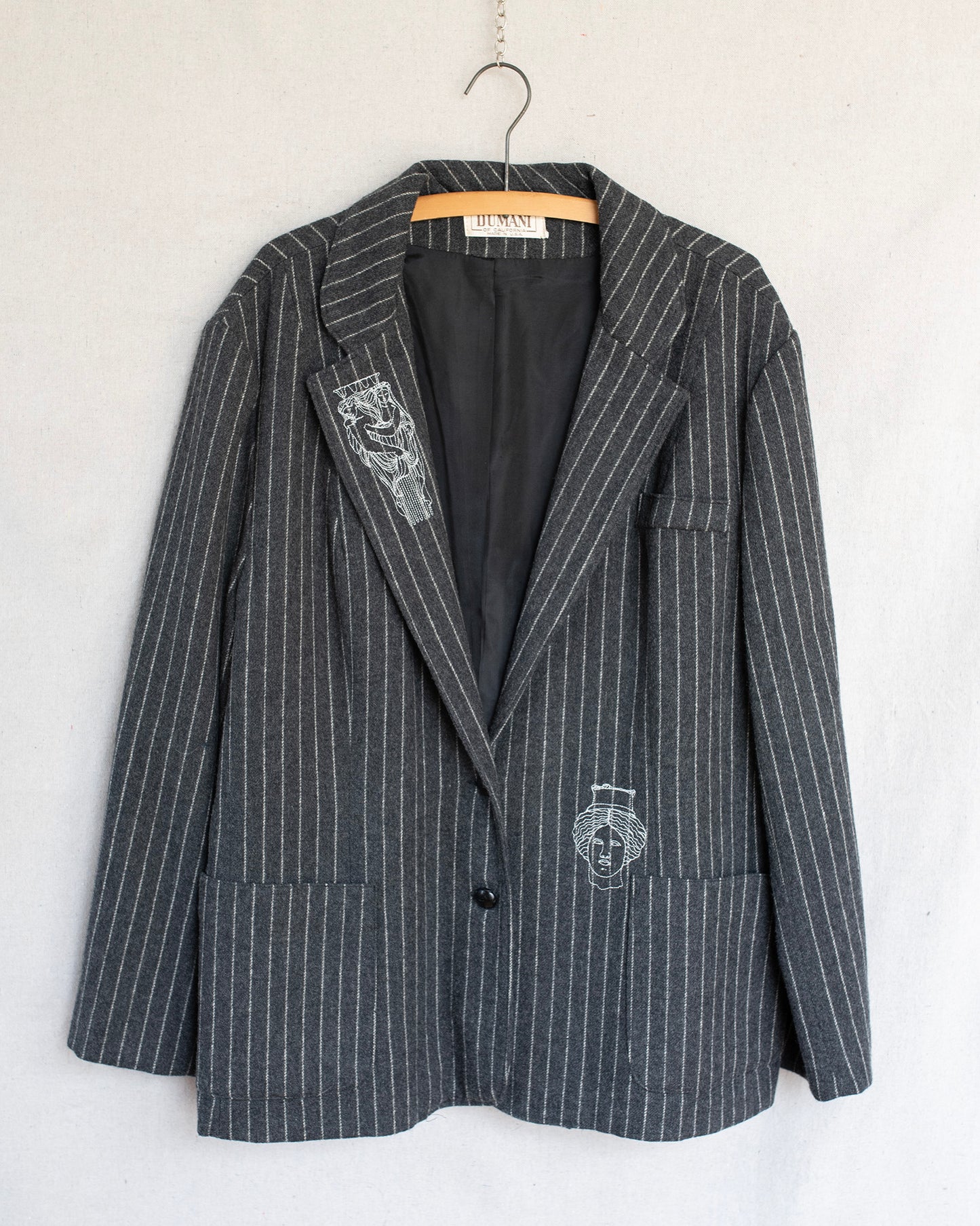 Gray pinstripe blazer with embroidered statues on a white background