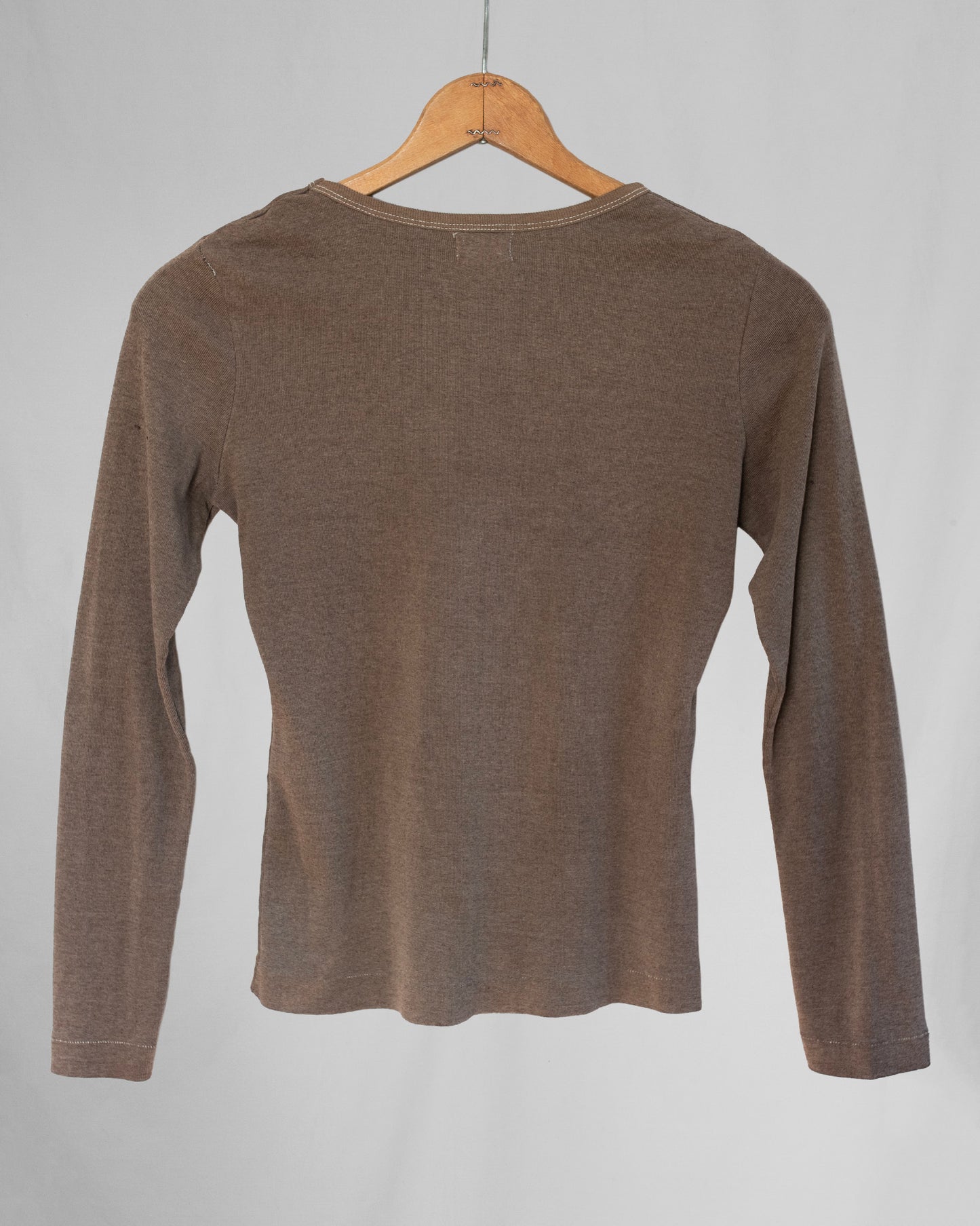 Brown long-sleeve shirt on a wooden hanger against a gray background