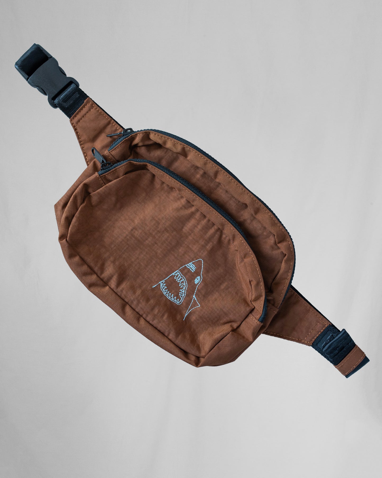 Fanny pack with shark embroidery on front pocket.