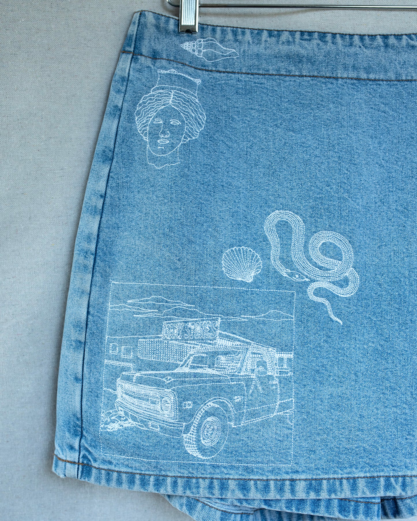 Blue denim shorts with embroideries on a gray background