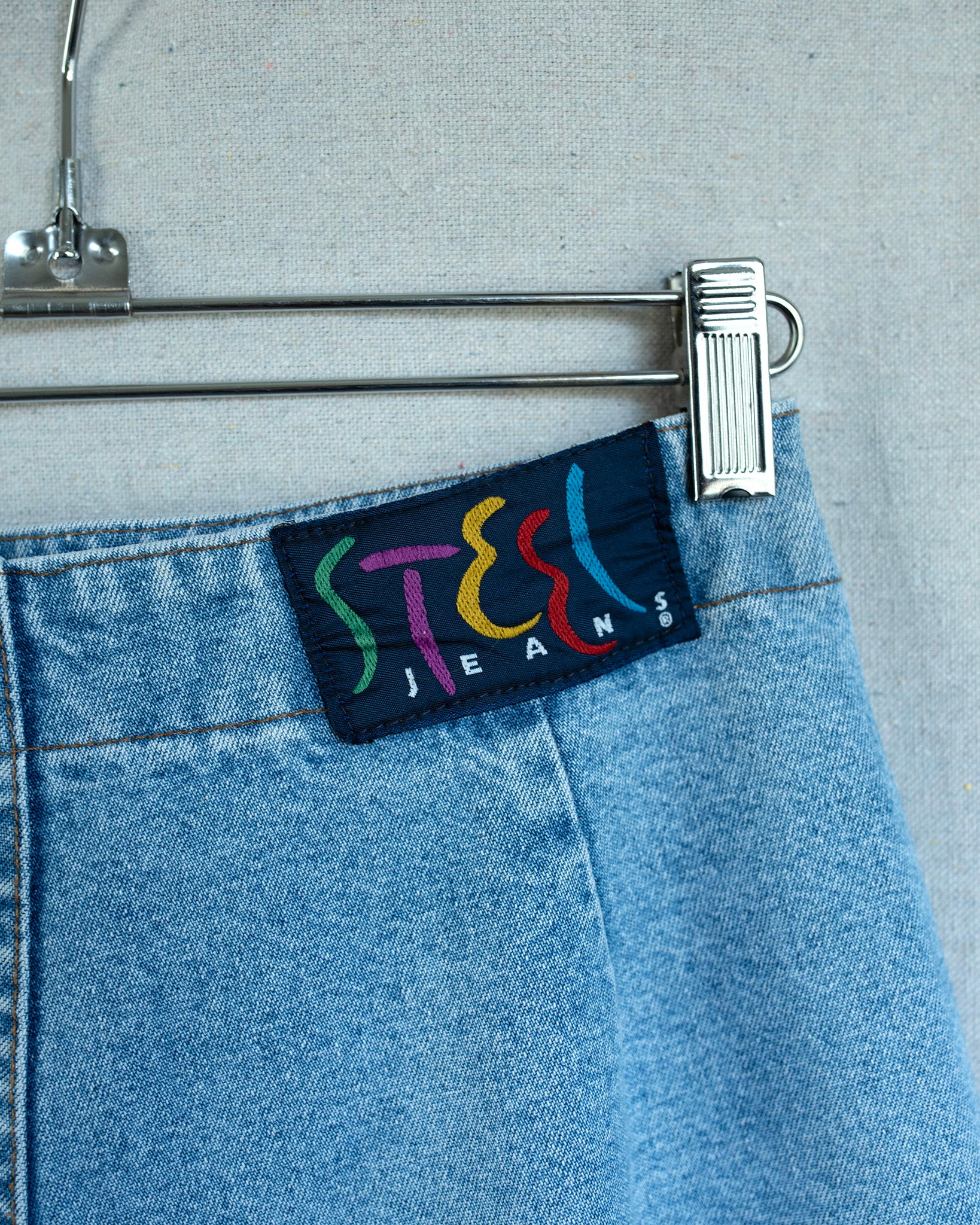 Close-up of a denim label with colorful text on a gray background