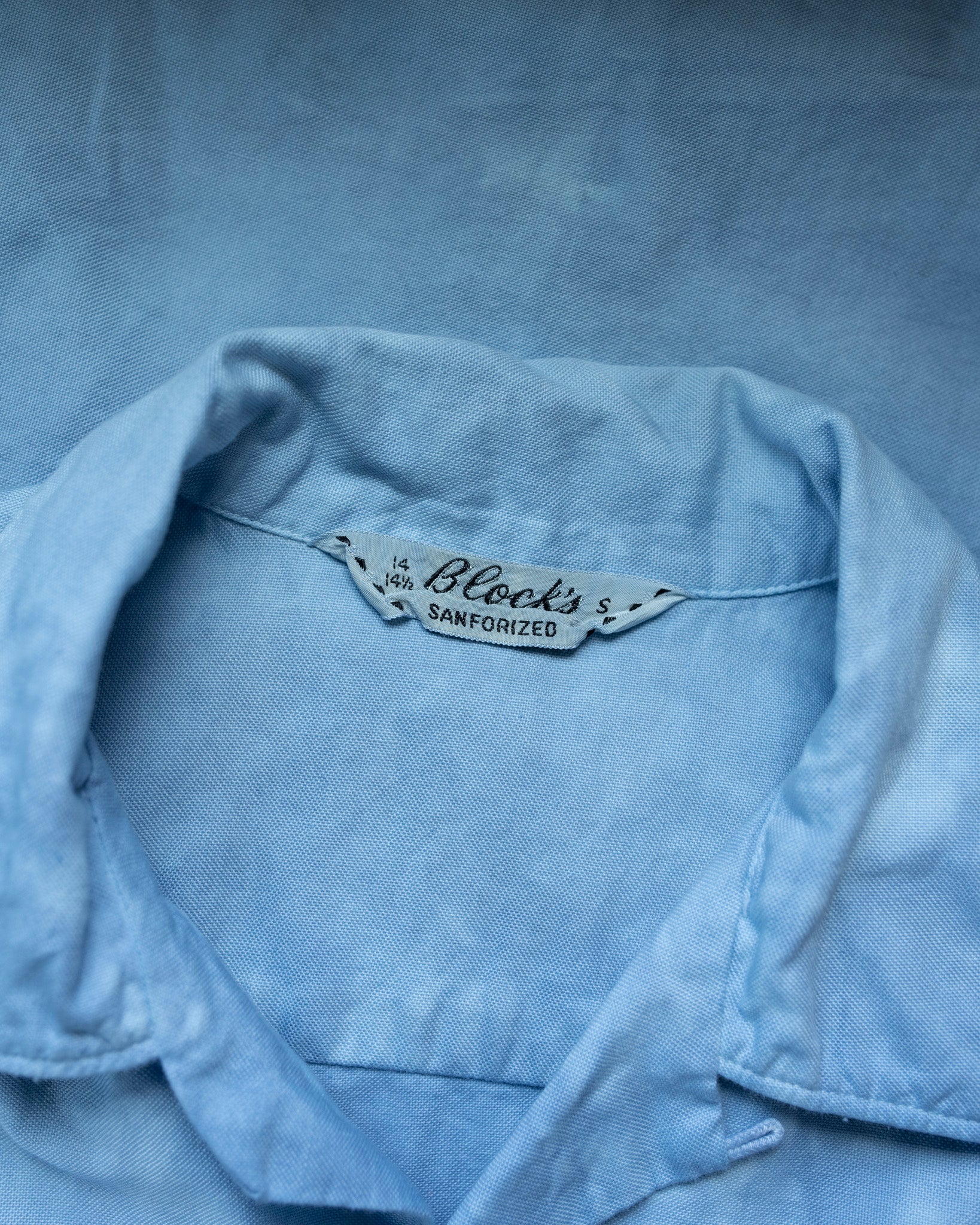 Close-up of a denim shirt with a brand label on a blue background