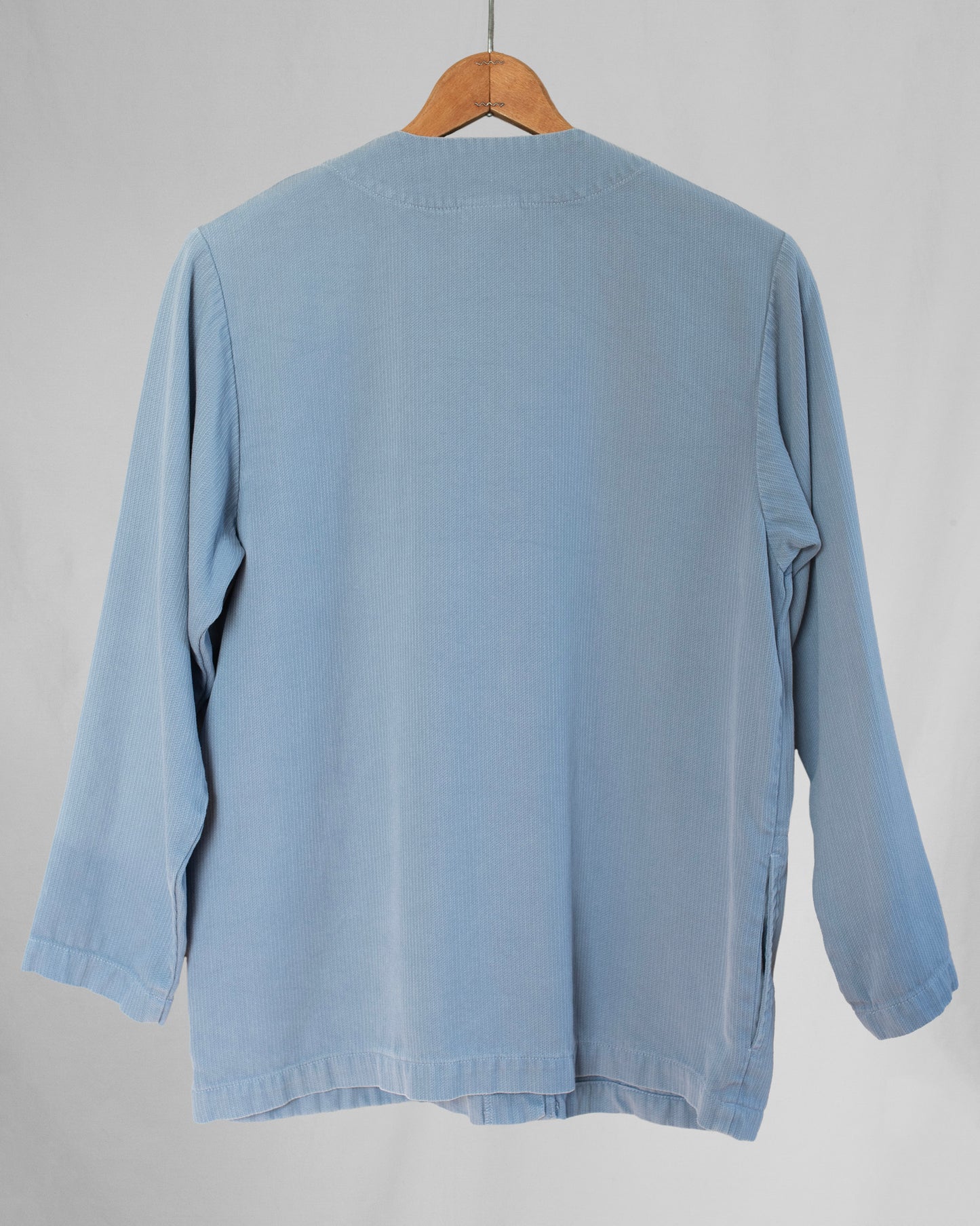 Light blue jacket on a wooden hanger against a gray background