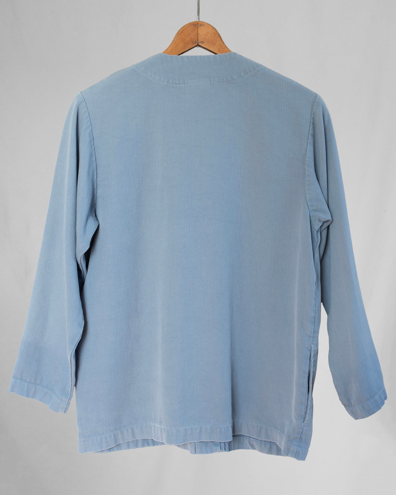 Light blue jacket on a wooden hanger against a gray background