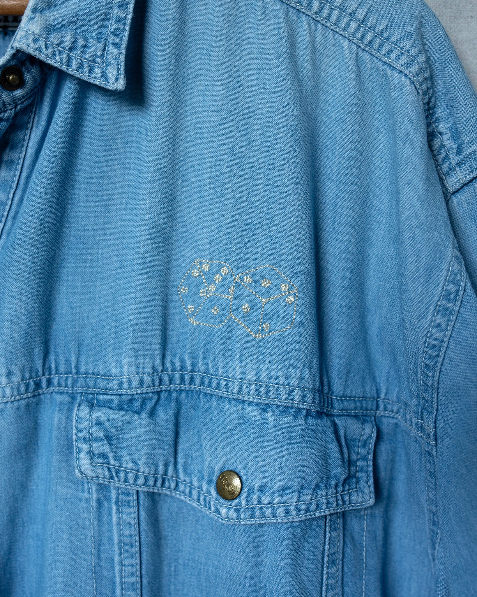 Blue denim jacket with a dice embroidery on the chest pocket