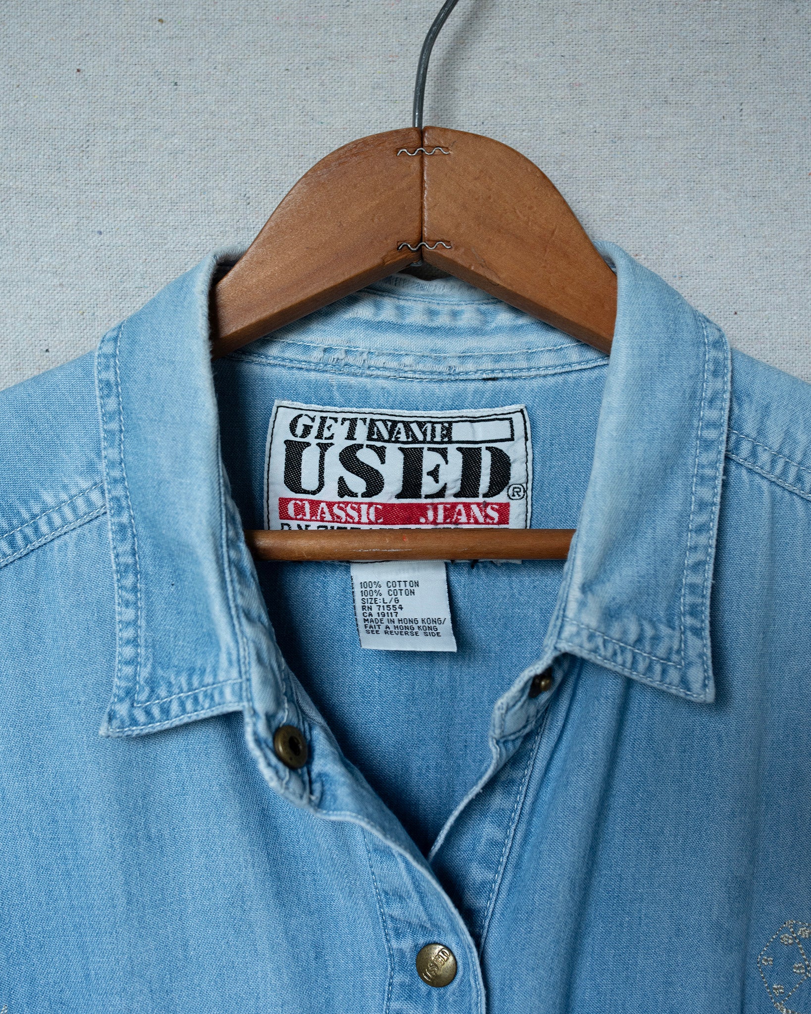 Blue denim shirt on a hanger with 'Used' brand label.