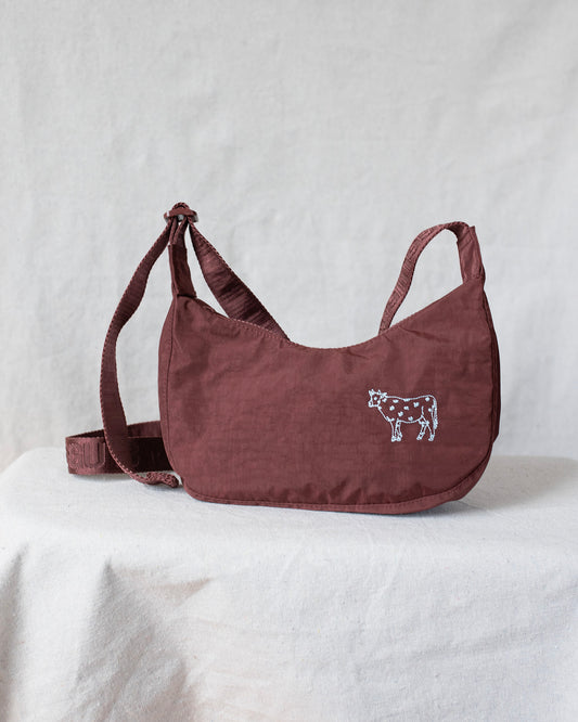 Small crossbody bag with a cow design on a white surface