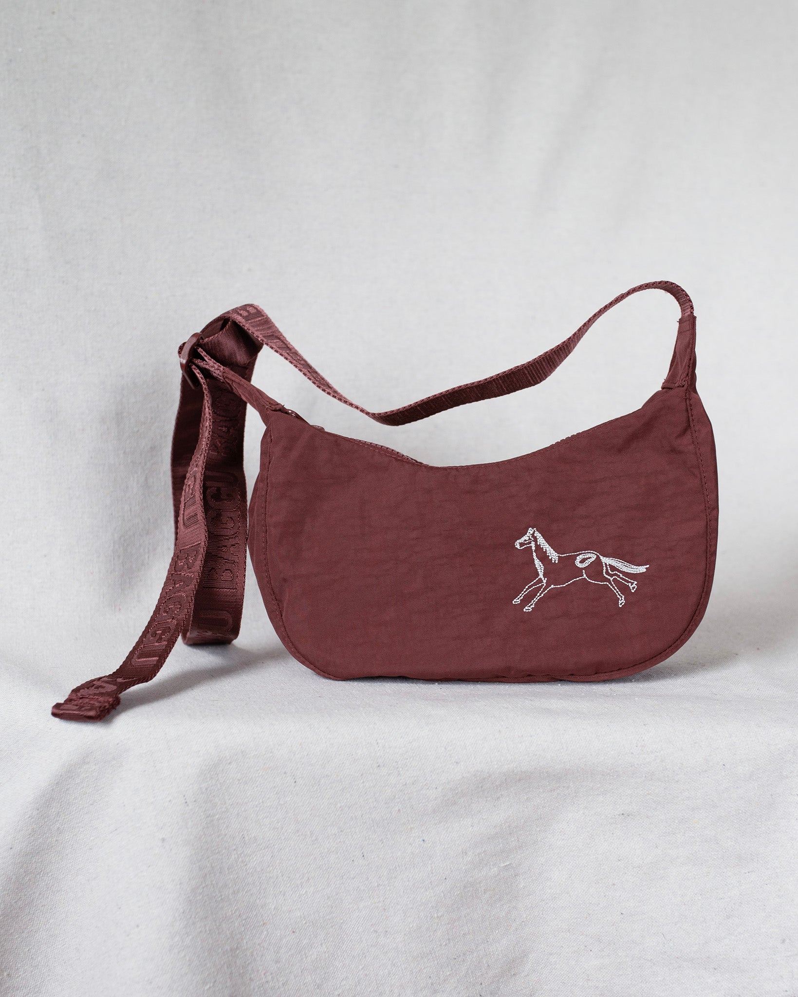 Mahogany crossbody bag with a horse embroidery on a light gray background