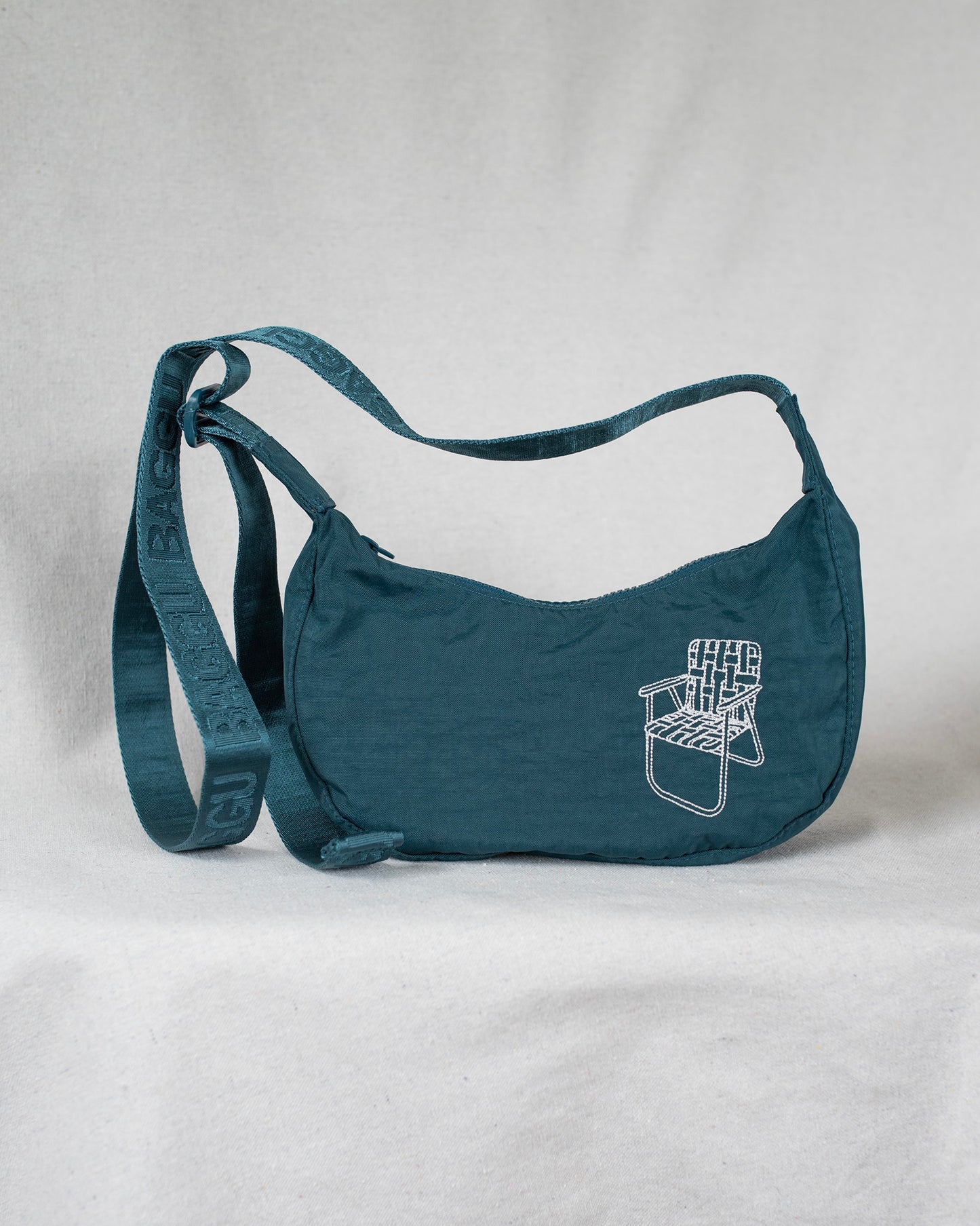 Deep sea colored cross body bag with a lawn chair embroidery