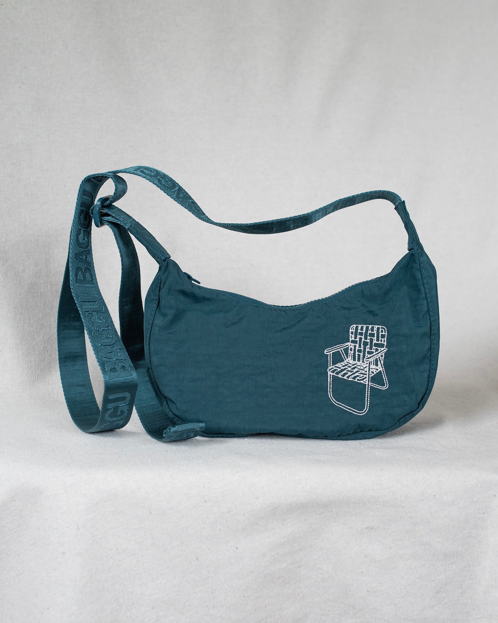 Deep sea colored cross body bag with a lawn chair embroidery